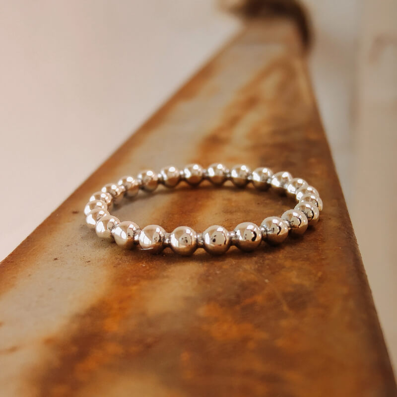 Sterling silver Western bead band ring on rustic background.