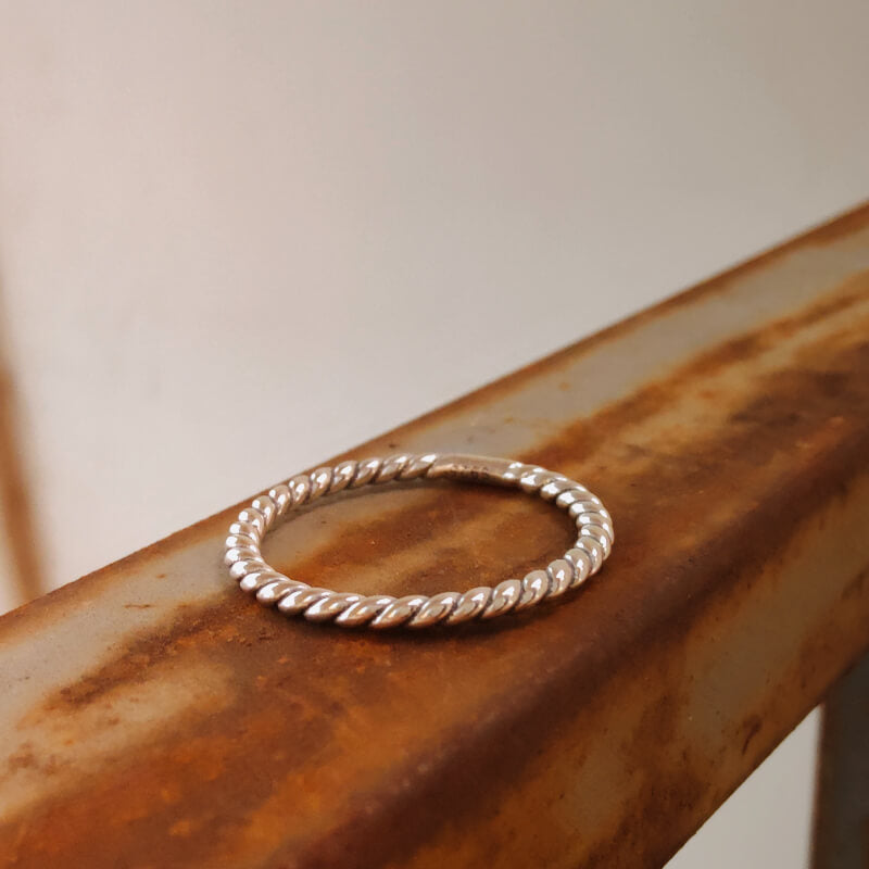 Sterling silver Western Twist Band Ring on rustic metal surface