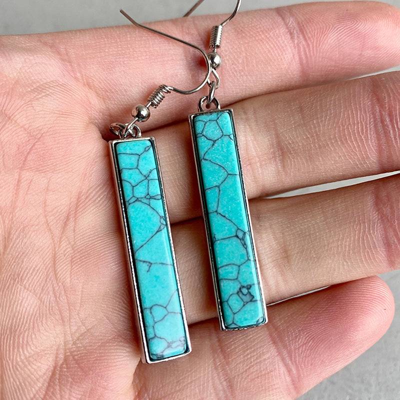 Long turquoise earrings in silver frame, showcasing intricate design.