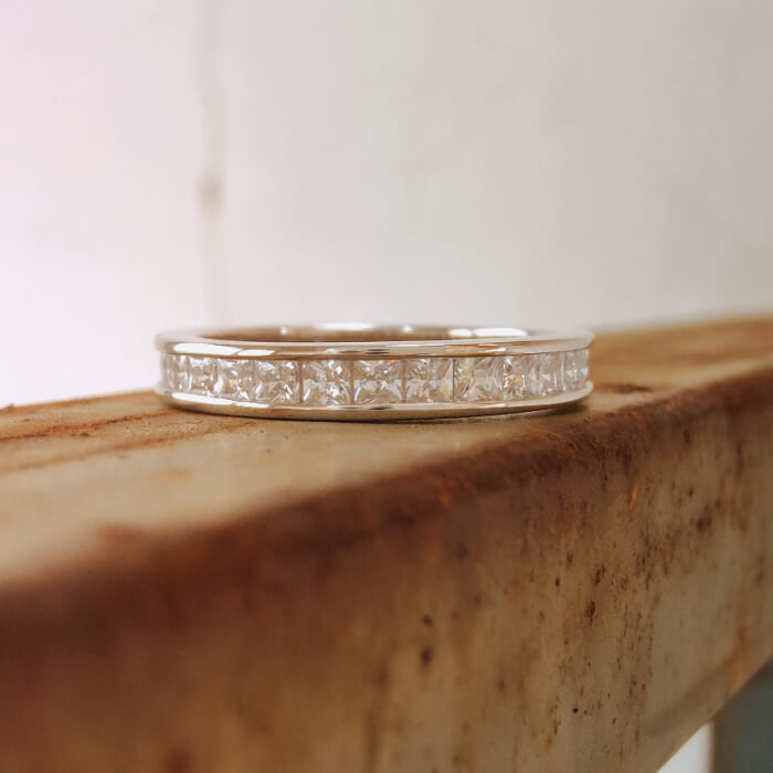 Silver stacker ring with diamond inlay on a rustic wooden surface