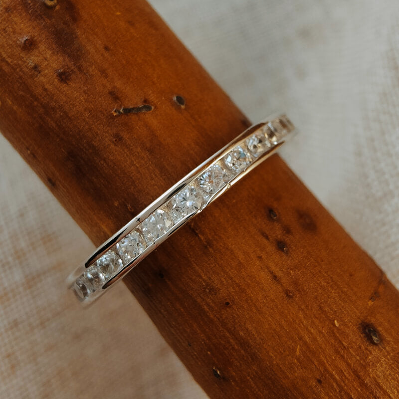 Sterling silver moissanite band ring on a wooden surface