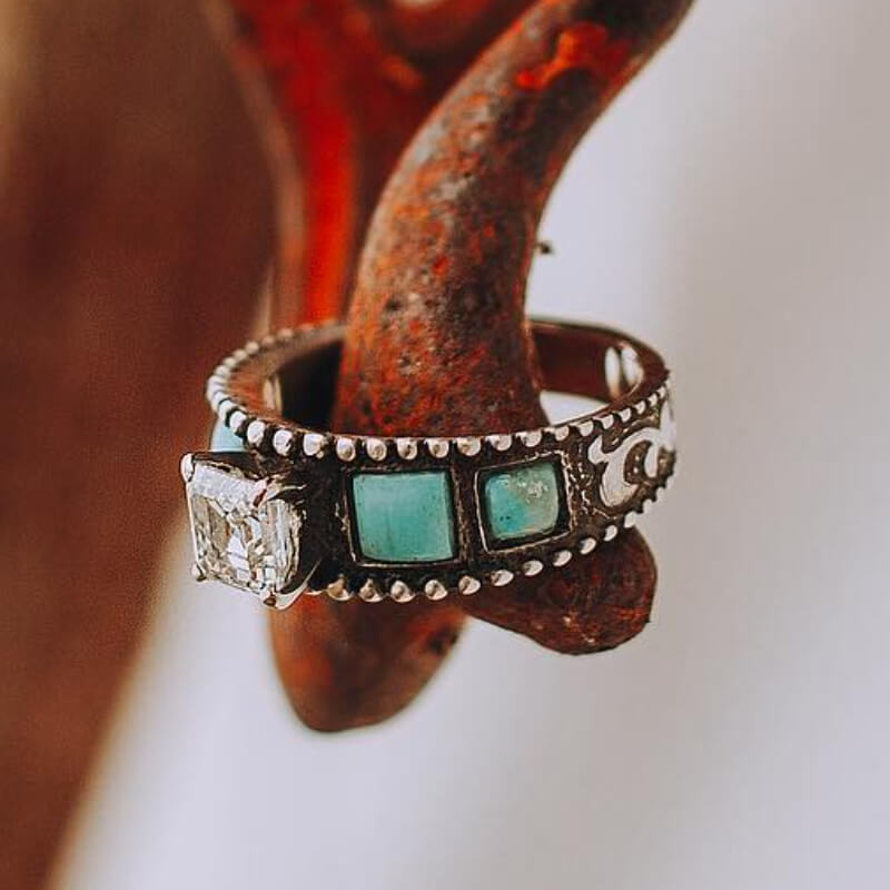 Square engraved turquoise and diamond ring on rustic display