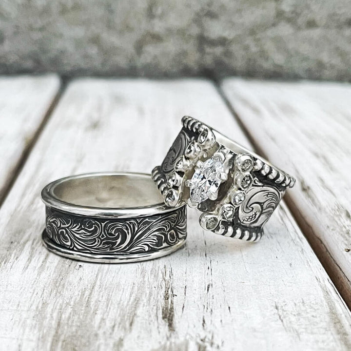 Intricate engraved silver engagement ring featuring marquise diamond centerpiece
