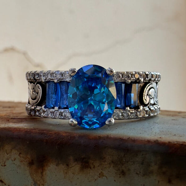 Oval blue sapphire ring with silver detailing and decorative band