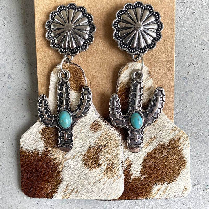 Cactus earrings with turquoise stone on cowhide print base and silver flower top.