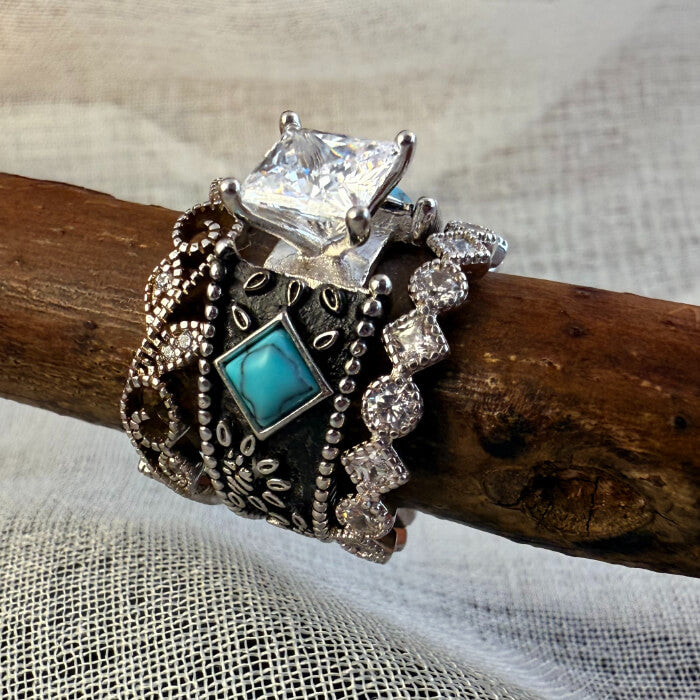 Three stacked Western rings featuring turquoise and diamond designs on a wooden branch