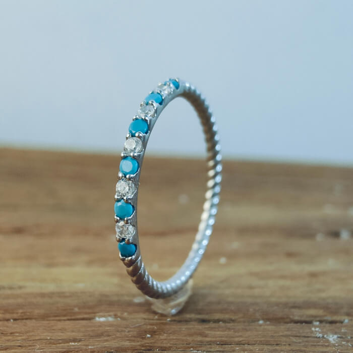 Delicate silver band ring with turquoise and zircon gemstones in a textured design.