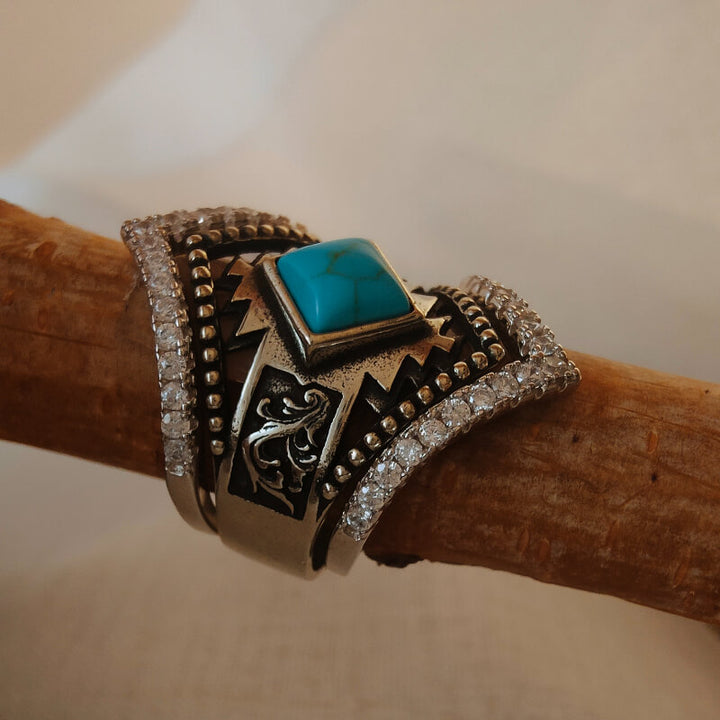 Sterling silver ring featuring a square turquoise stone with decorative accents