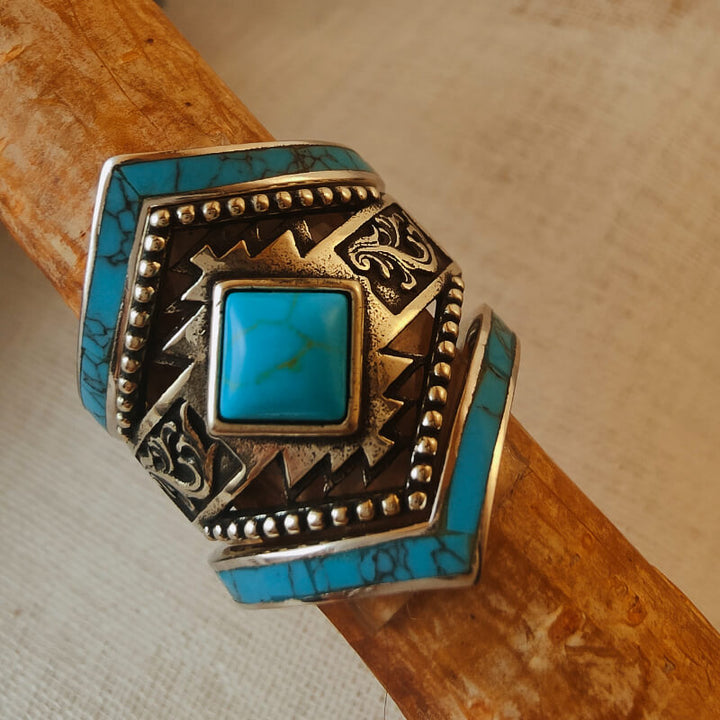 Square turquoise ring with intricate silver accents and Western-inspired design