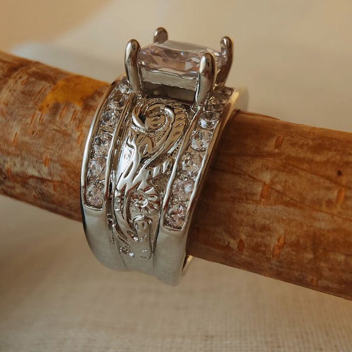 Wide band silver ring with zircon stone and intricate floral engravings on wood