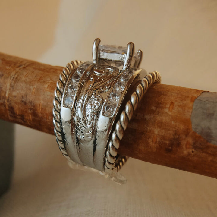 Engraved wide band ring with zircon stone on rustic wooden setting.