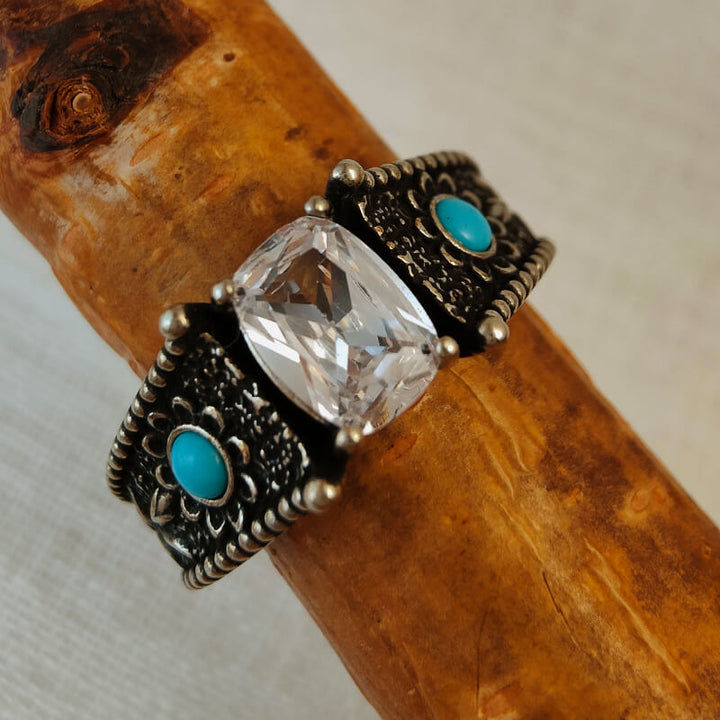 Turquoise and clear stone engagement ring with intricate silver filigree.