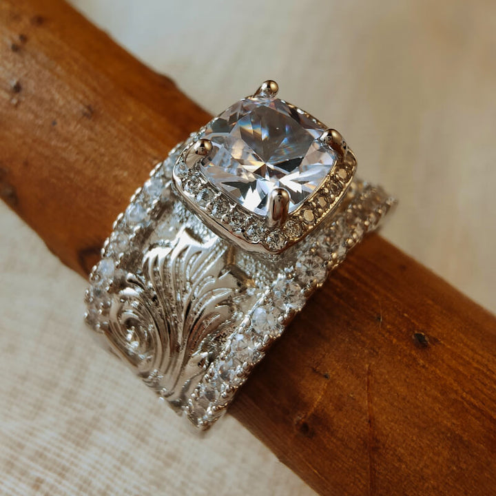 Sparkling silver ring with floral engravings and large zircon stone centerpiece.
