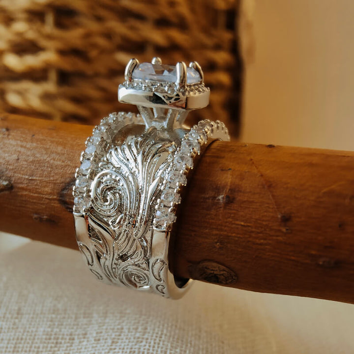 Silver ring with flower engravings and large zircon stone on a wooden surface