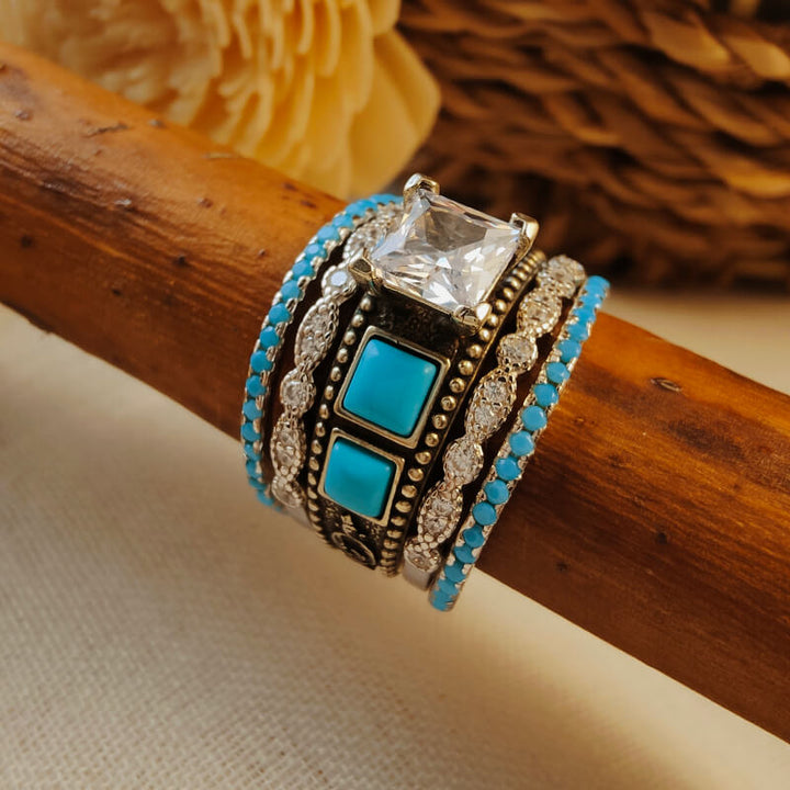 Silver ring set featuring turquoise squares and a large zircon centerpiece