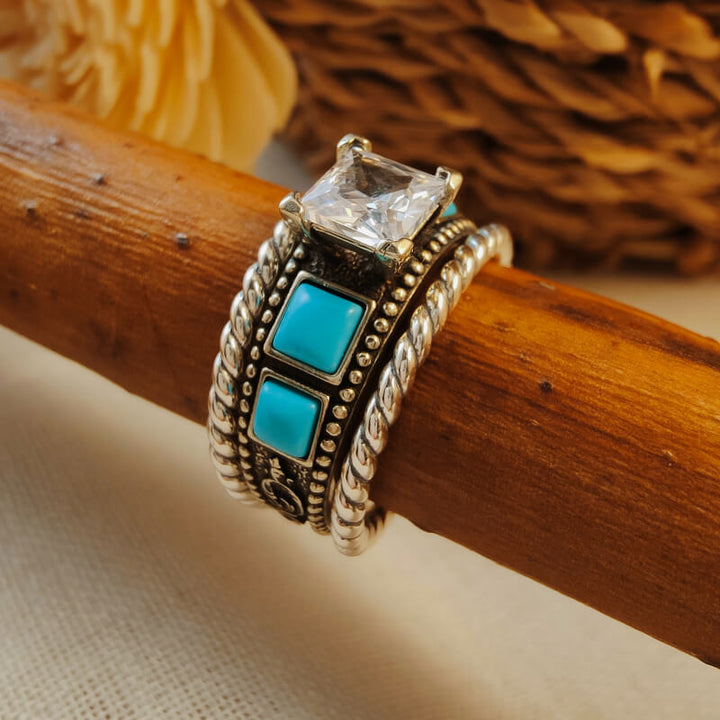 Twisted silver ring set with square turquoise gemstone and diamond accent.
