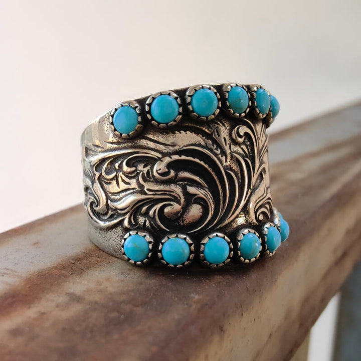 Intricate floral engraved silver ring adorned with turquoise gemstones