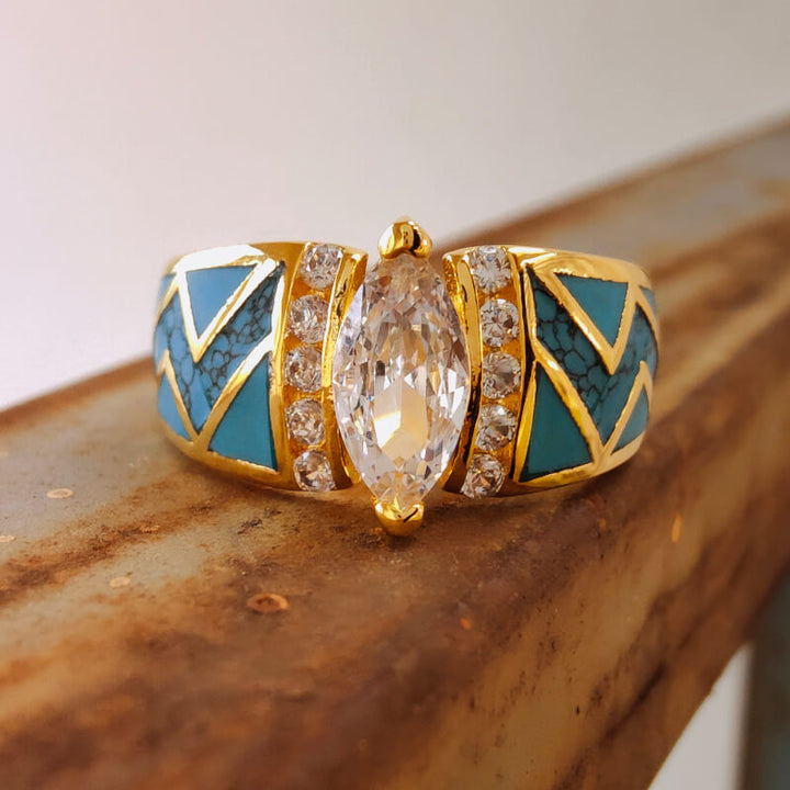 Gold turquoise ring with marquise diamond and geometric inlay design.