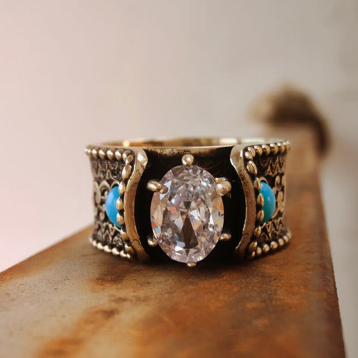 Handcrafted turquoise diamond ring with ornate wave design and turquoise on rustic background.