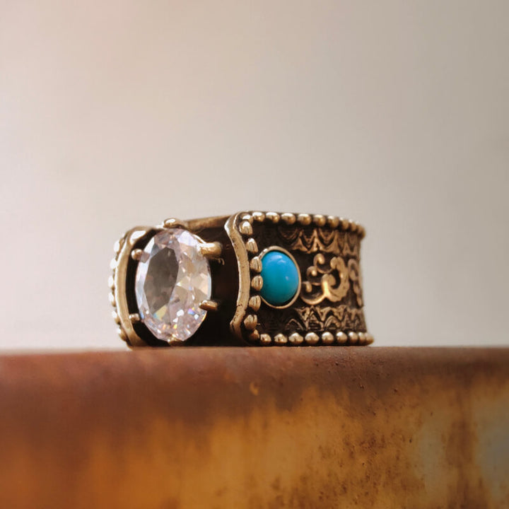 Close-up of wave engraved copper ring with diamond and turquoise accent.