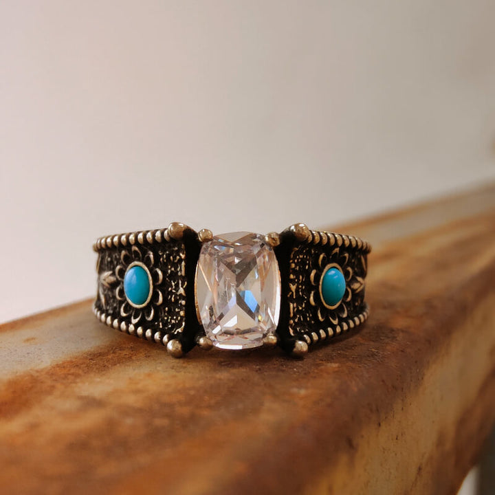 Western-style turquoise and clear stone engagement ring with detailed metalwork.