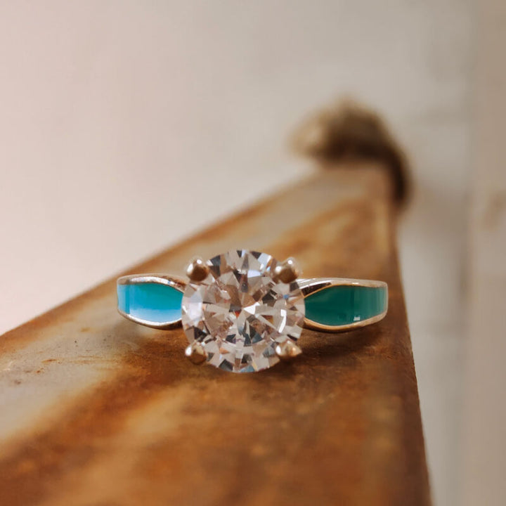 Sterling silver engagement ring with round moissanite and turquoise side accents.