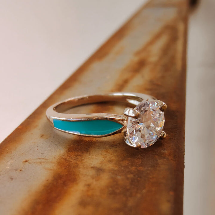 Sterling silver moissanite engagement ring with turquoise accents on a brown surface.