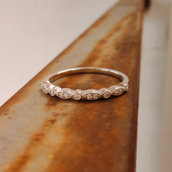 Close-up of sterling silver vintage diamond band ring on textured metal surface.