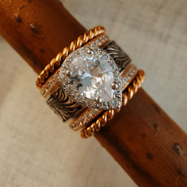 Rose gold pear engagement ring set with diamond accents and twisted bands.