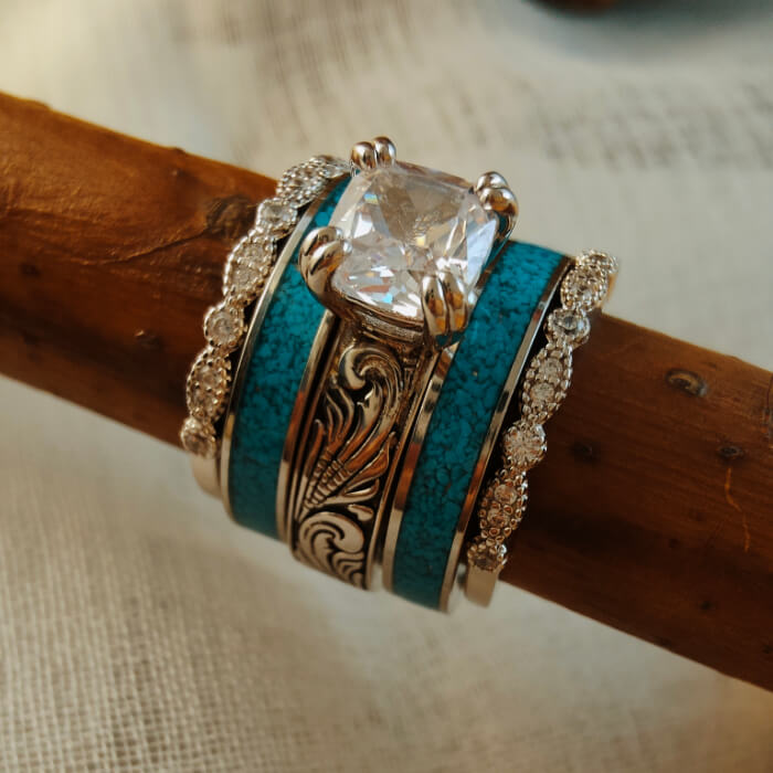 Sterling silver ring set with turquoise and diamond accents on a wooden stick