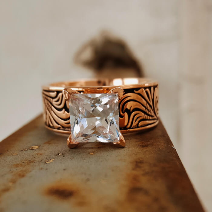 Rose gold wedding ring with detailed floral engravings and large square diamond-like zircon.