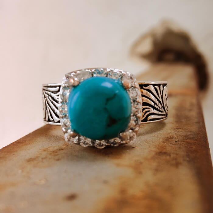 Turquoise ring with diamond halo and floral design on silver-black band.