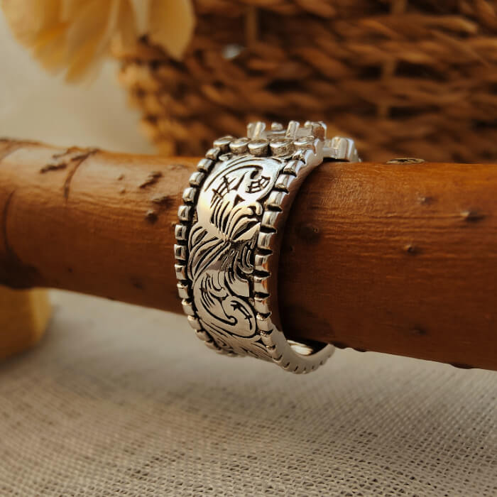 Western-style wide band ring featuring intricate floral engravings.