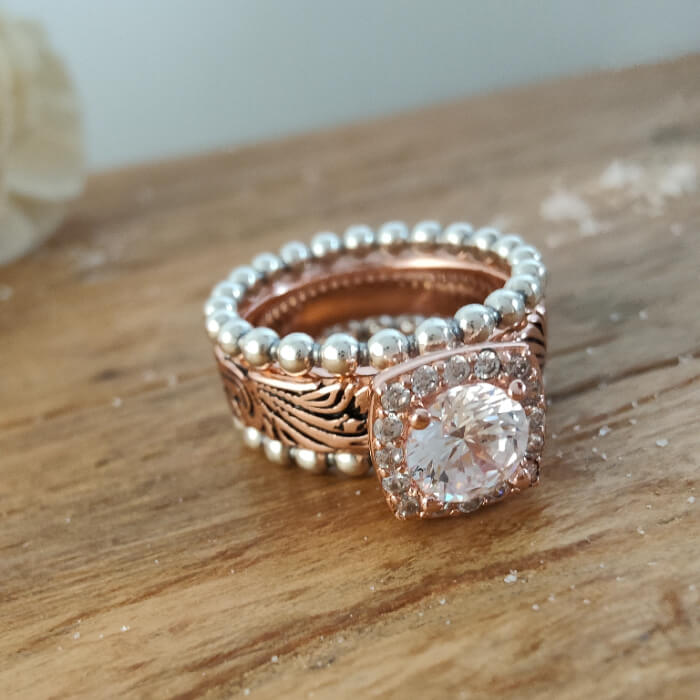 Rose gold and silver bead ring set with intricate band and large moissanite stone.