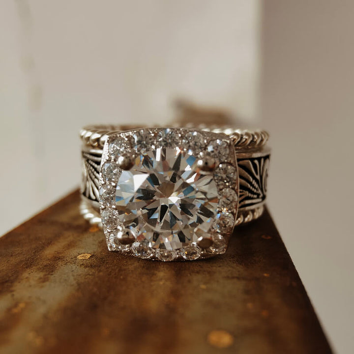 Sterling silver engagement ring with large diamond halo and detailed floral engravings.
