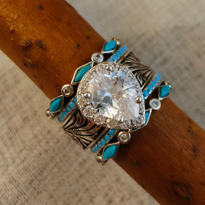 Vintage pear cut turquoise wedding ring featuring a diamond center and floral embellishments.