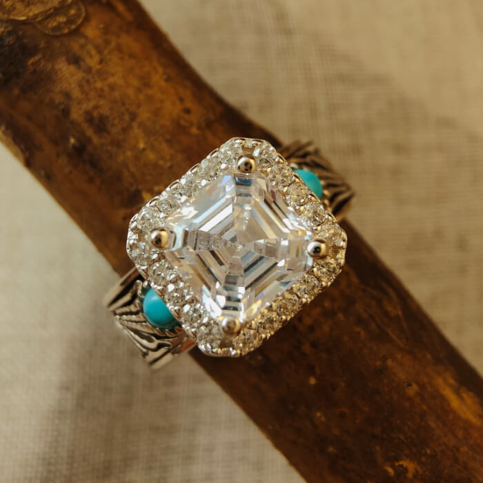 Radiant cut diamond engagement ring with turquoise accents on silver-black band