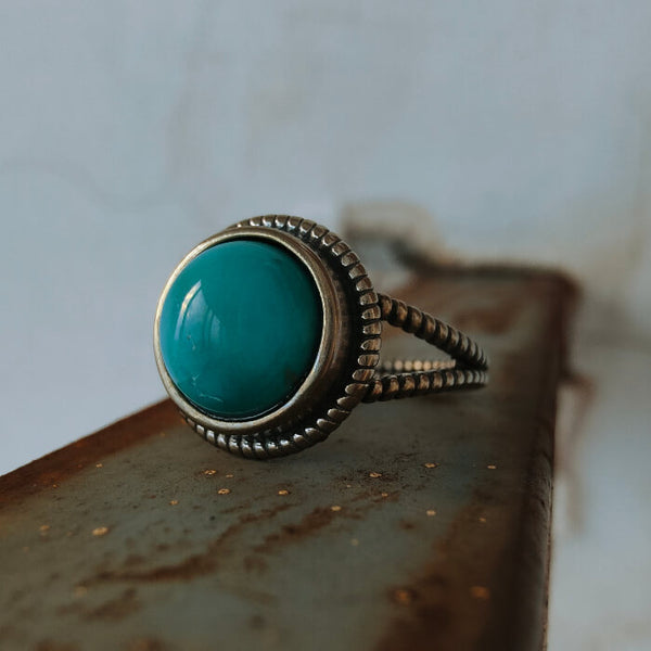 Women's round turquoise ring with silver band and detailed setting