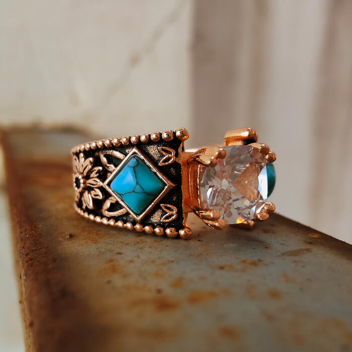Engraved turquoise engagement ring with zircon accents on a rose gold band.