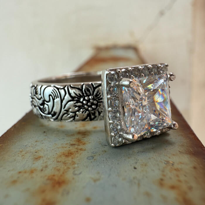 Square engagement ring with floral design and diamond halo, showcasing a beautiful zircon stone.