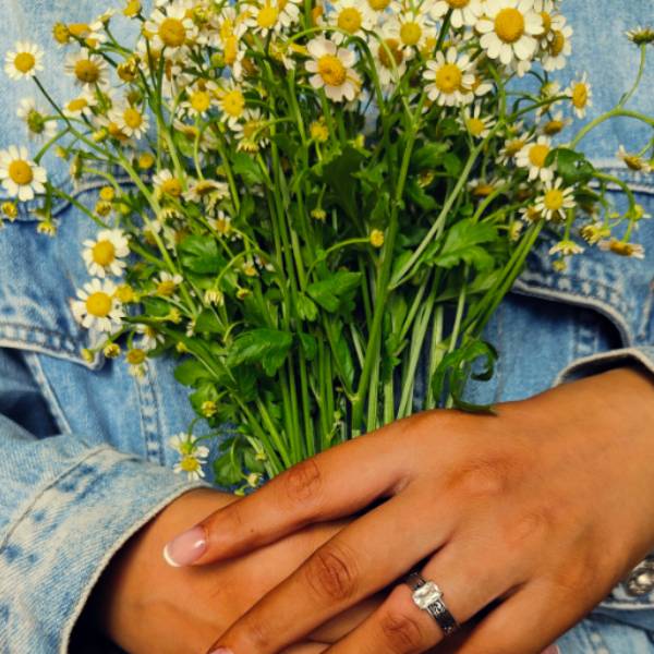 Woman holding bouquet of daisies showcasing a Western engagement ring with zircon stone