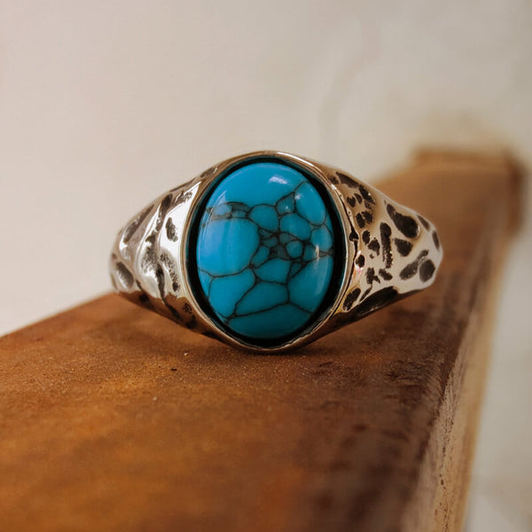 Steel oval turquoise ring with blue stone on a wooden surface