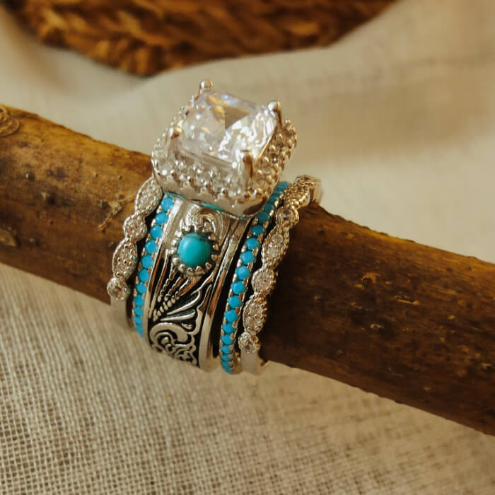 Diamond engagement ring with turquoise bands on a wooden display