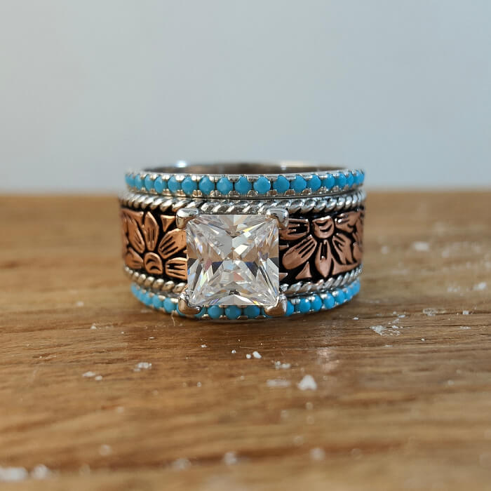 Intricately designed rose gold engagement ring with floral engravings and turquoise accents