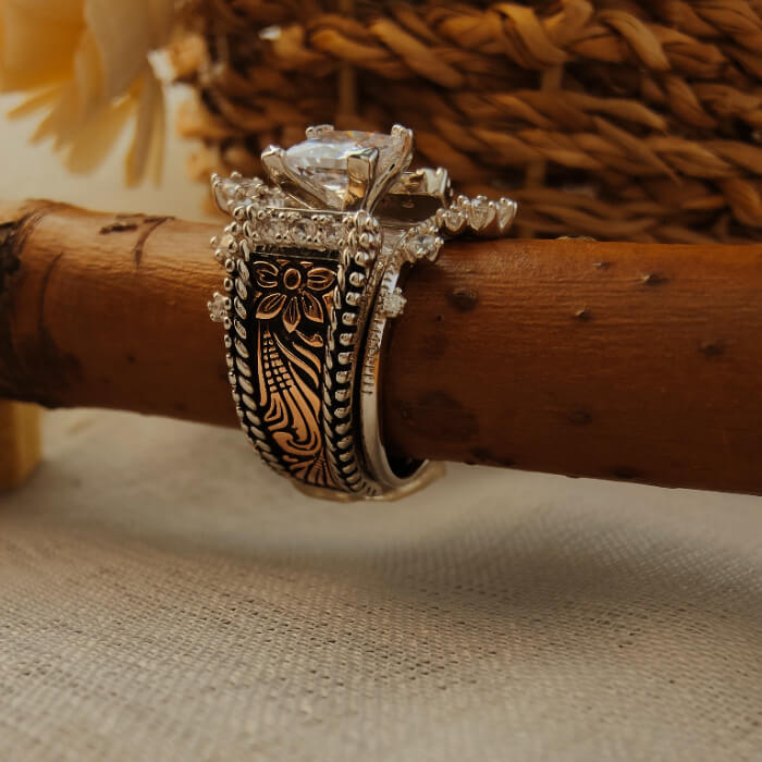 Sterling silver flower engraved ring with diamond accents on a wooden surface.