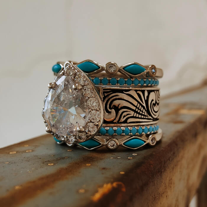 Vintage turquoise wedding ring with pear-shaped diamond and detailed floral engravings.