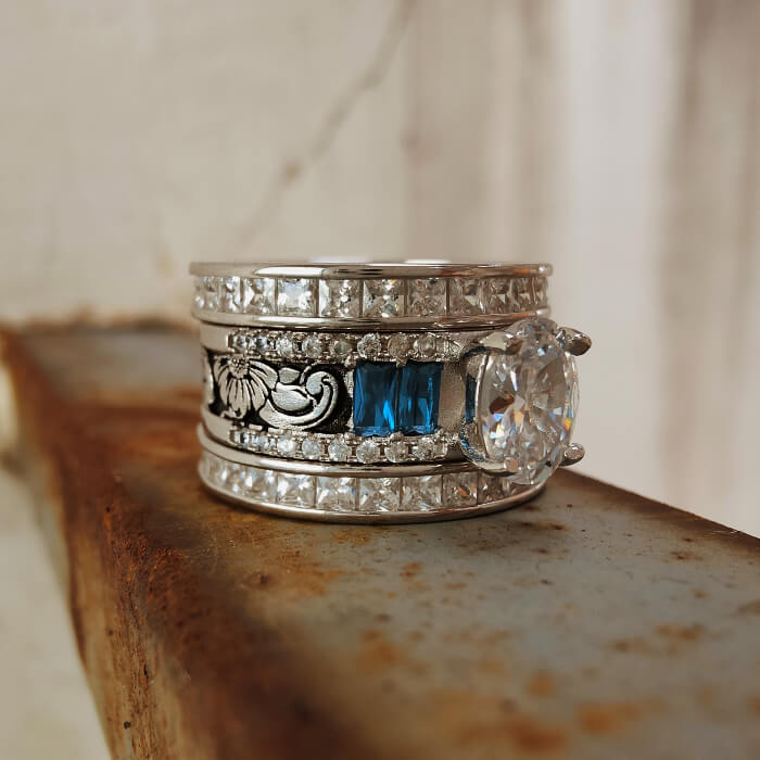 Flower engraved wide band engagement ring with oval diamond and blue sapphire accents