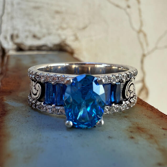 Decorative blue sapphire ring with silver band and intricate design