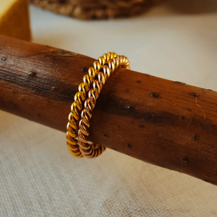 Rose gold steel twist band ring on wooden surface