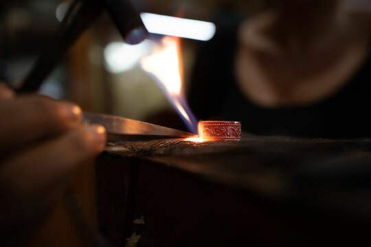 Jeweler crafting a customized ring with flame and metal tools in workshop